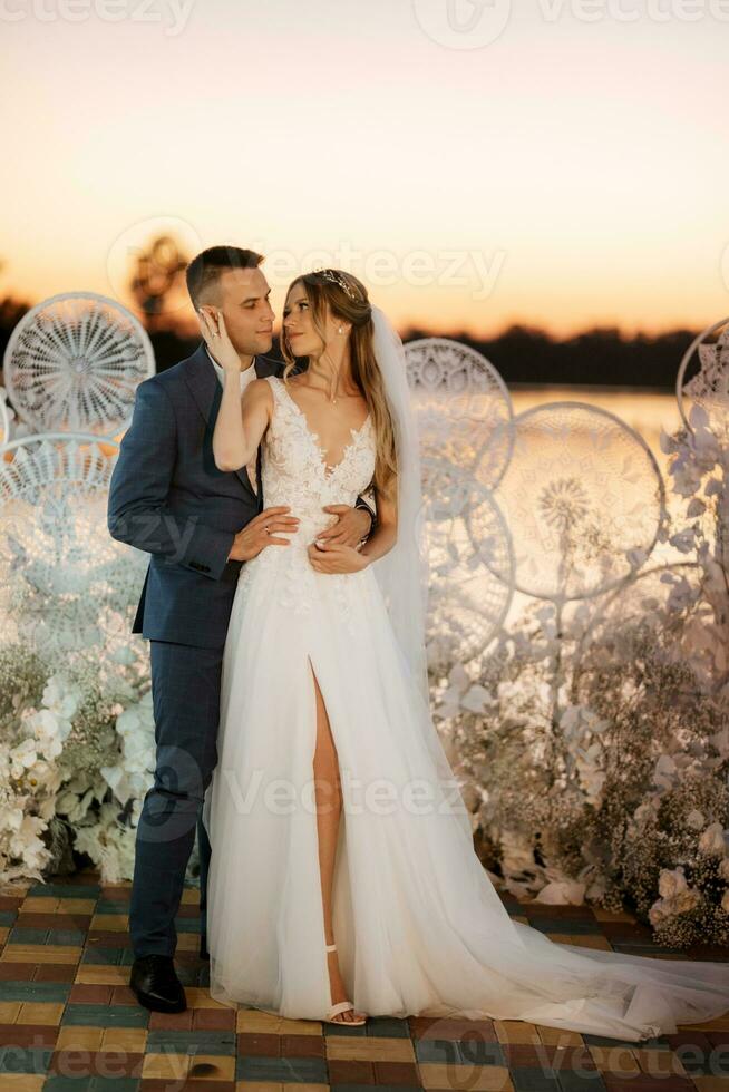 novia y novio contra el telón de fondo de una puesta de sol amarilla foto