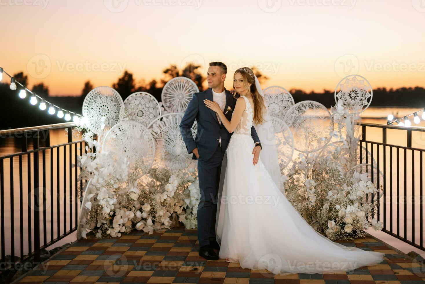 novia y novio contra el telón de fondo de una puesta de sol amarilla foto