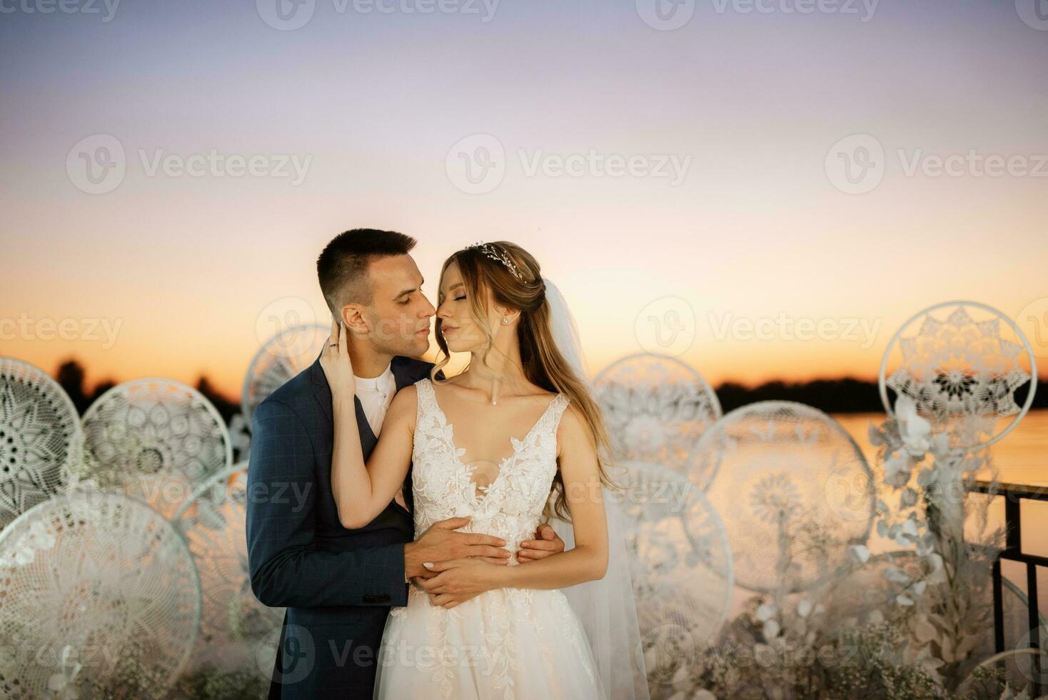 novia y novio contra el telón de fondo de una puesta de sol amarilla foto