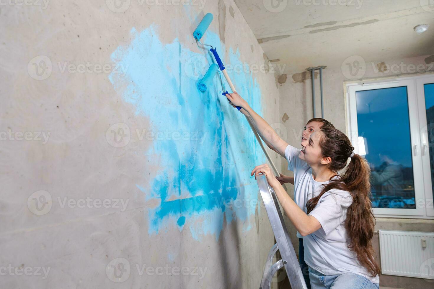 Pareja en nuevo hogar durante reparar trabajos pintura pared juntos.  contento familia participación pintar rodillo pintura pared con azul color  pintar en nuevo casa. hogar renovación bricolaje renovar hogar concepto.  25872610 Foto