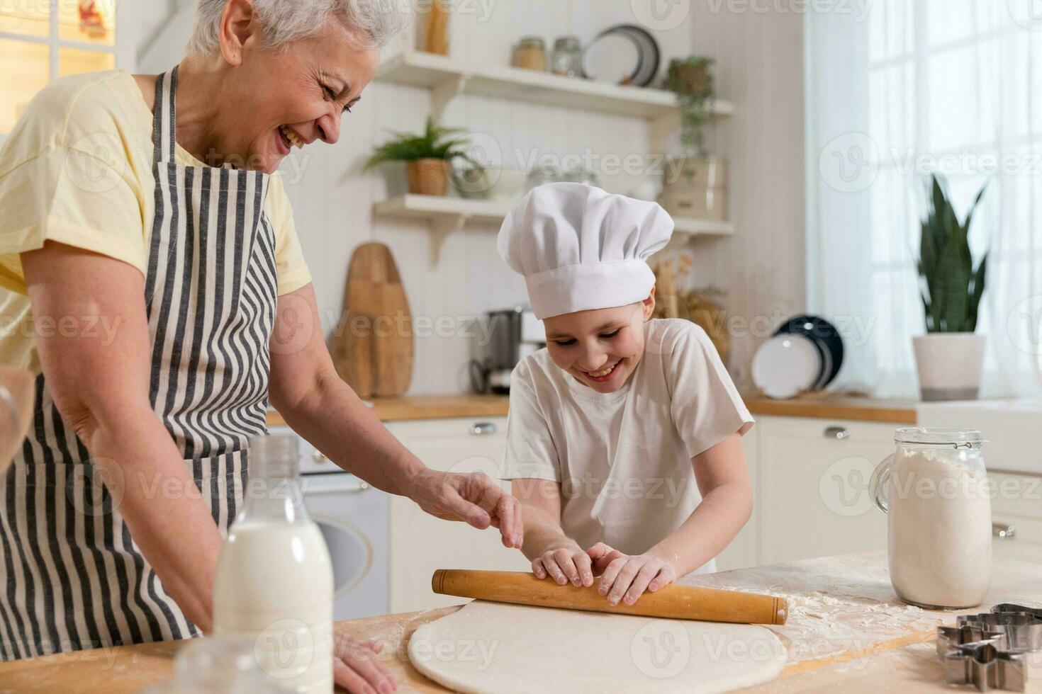 Happy family in kitchen. Grandmother and granddaughter child cook in kitchen together. Grandma teaching kid girl roll out dough bake cookies. Household teamwork helping family generations concept. photo