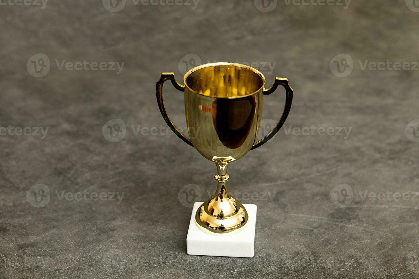 Simply design winner or champion gold trophy cup on concrete stone grey background. Victory first place of competition. Winning or success concept. Top view copy space. photo