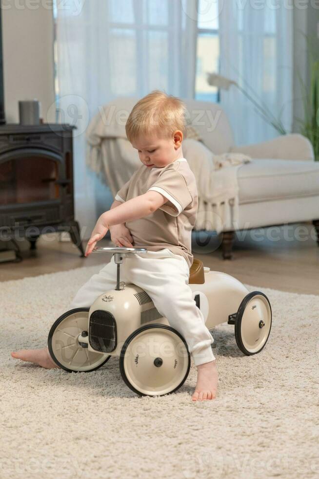 Happy child at home. Little toddler boy driving big vintage toy car and having fun. Smiling kid playing at home. Baby boy playing with toy in living room indoors. photo