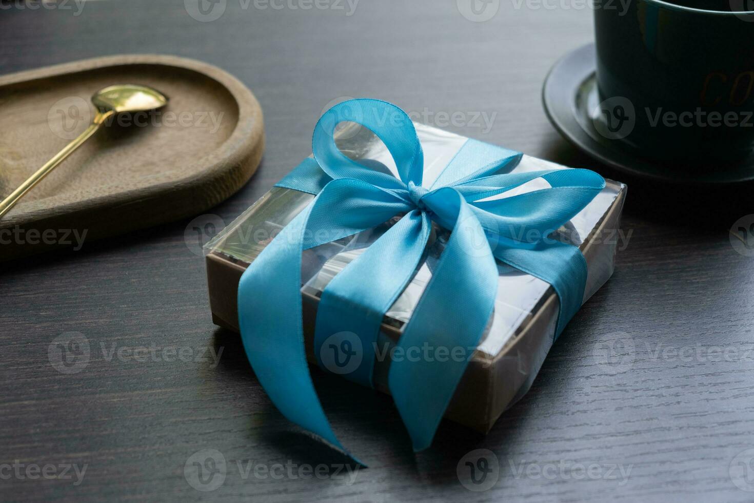 Gift box with bow with chocolate craft candies inside on dark table with tea cup photo