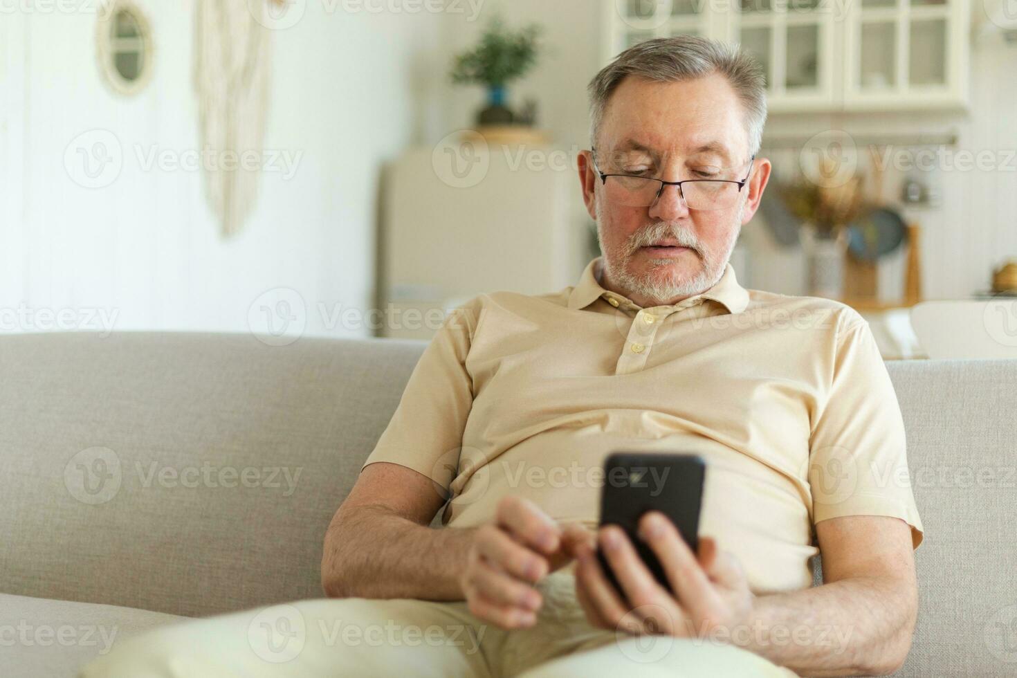 Happy middle aged senior man holding using smartphone touch screen typing scroll page. Stylish older mature beard grandfather with cell phone using internet social media apps at home. Shopping online. photo