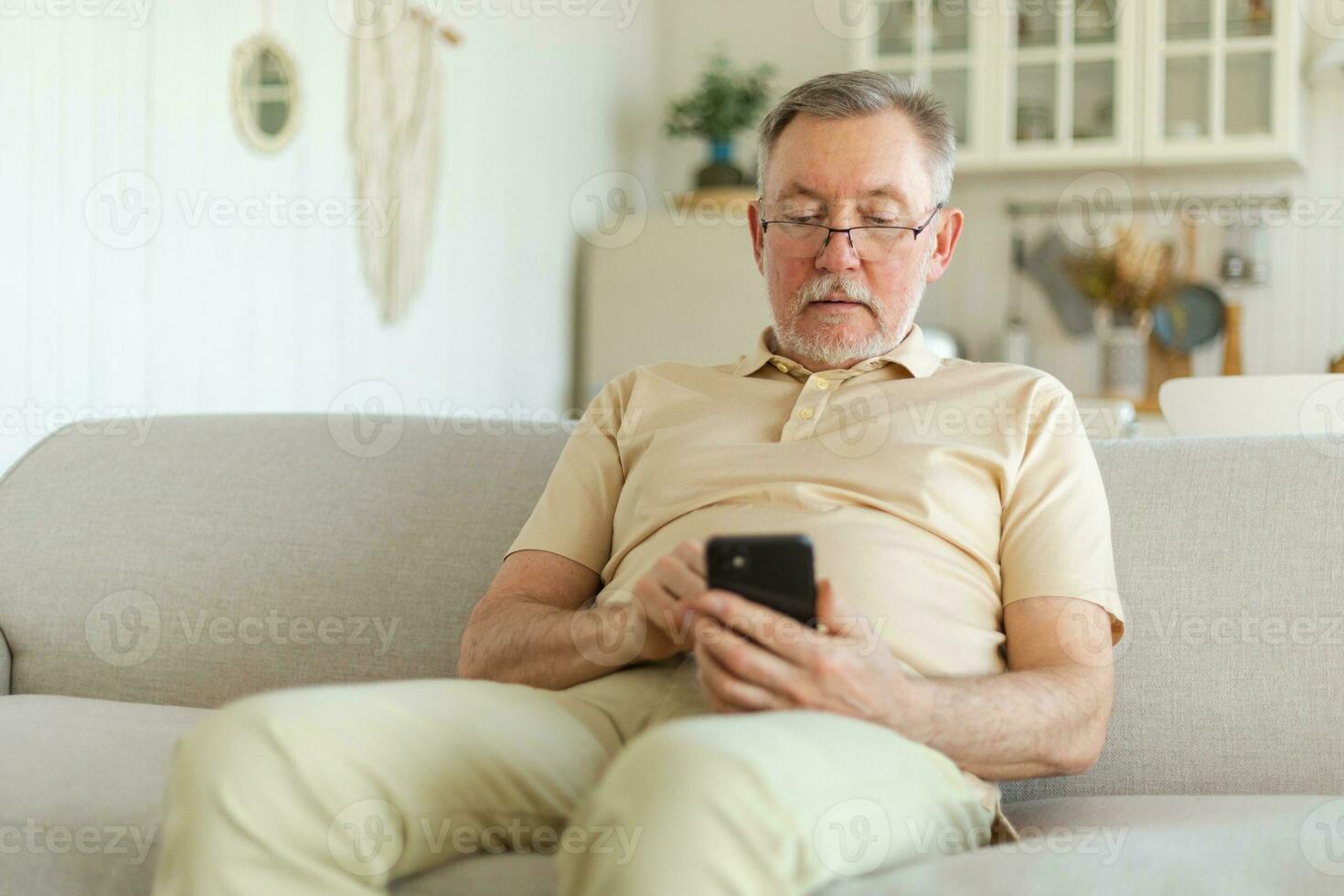 Happy middle aged senior man holding using smartphone touch screen typing scroll page. Stylish older mature beard grandfather with cell phone using internet social media apps at home. Shopping online. photo