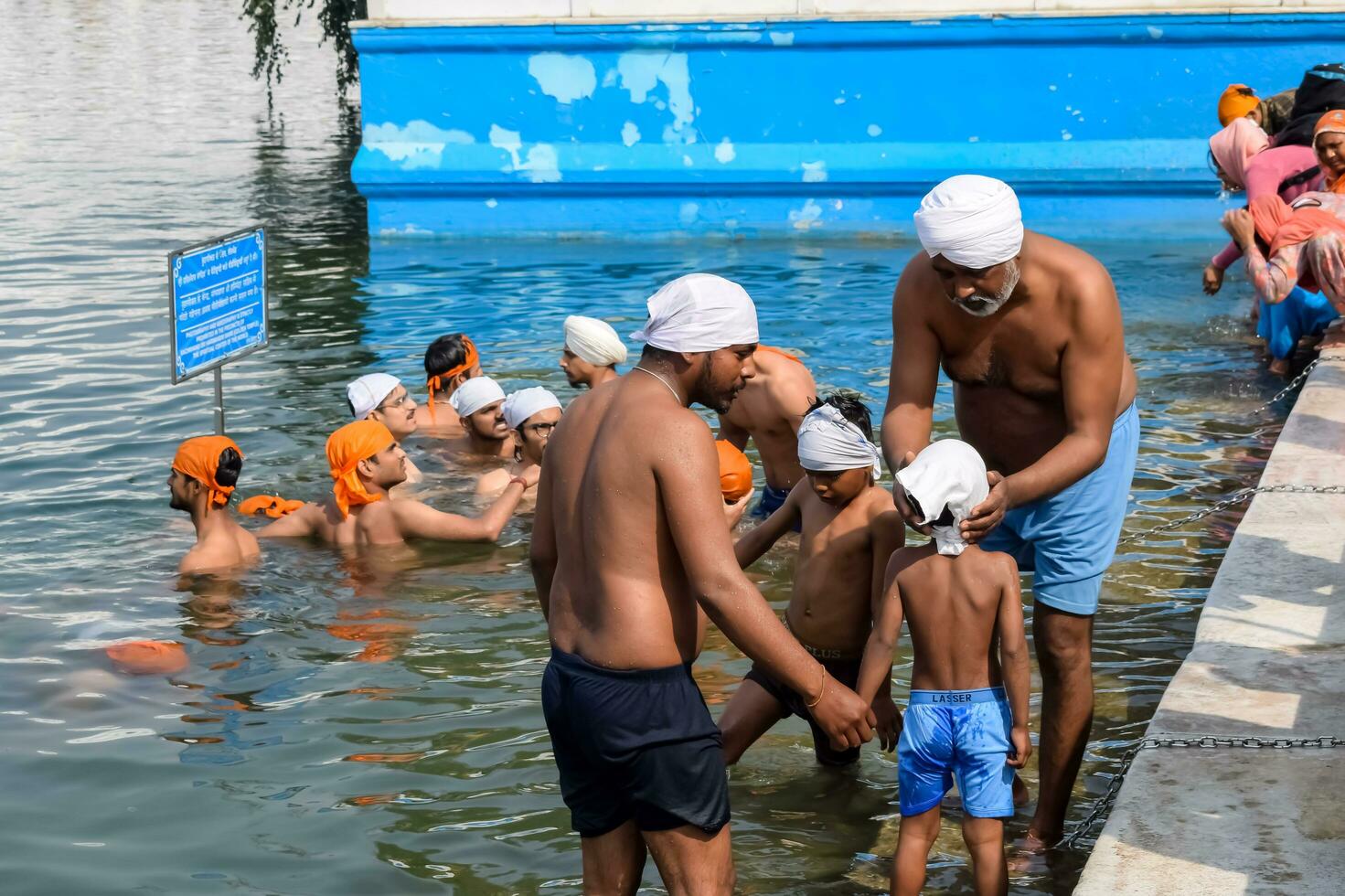 Amritsar, India - February 26 2023 - Unidentified devotees taking holy dip in sarovar at Golden Temple - Harmandir Sahib in Amritsar, Punjab, India, Famous indian sikh landmark, Golden Temple photo