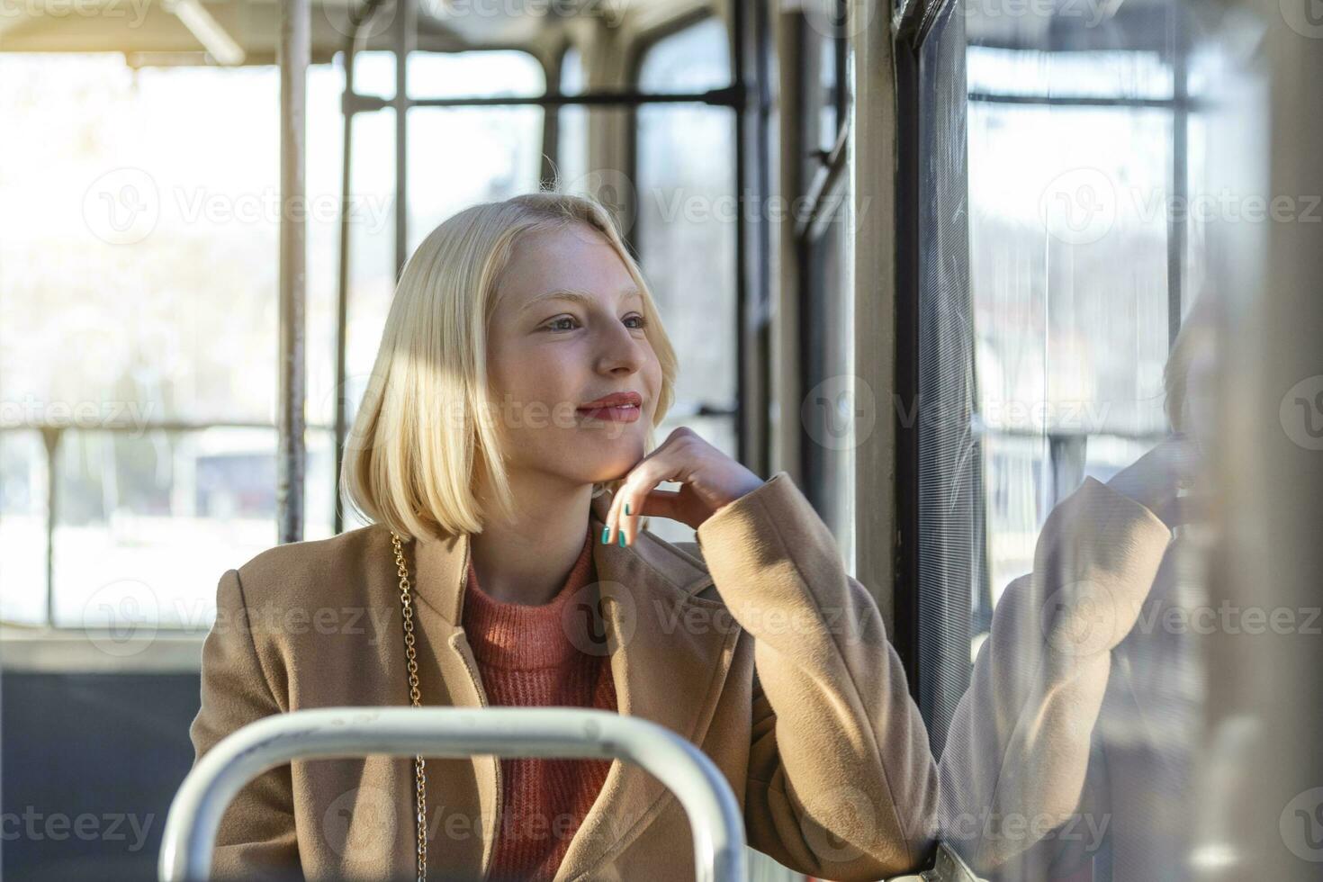 One Young Woman Smiling in a Bus While looking through the window Beautiful Young Woman Taking Bus to Work. Passenger in the Bus or Train, Technology Lifestyle, Transportation and Traveling Concept. photo