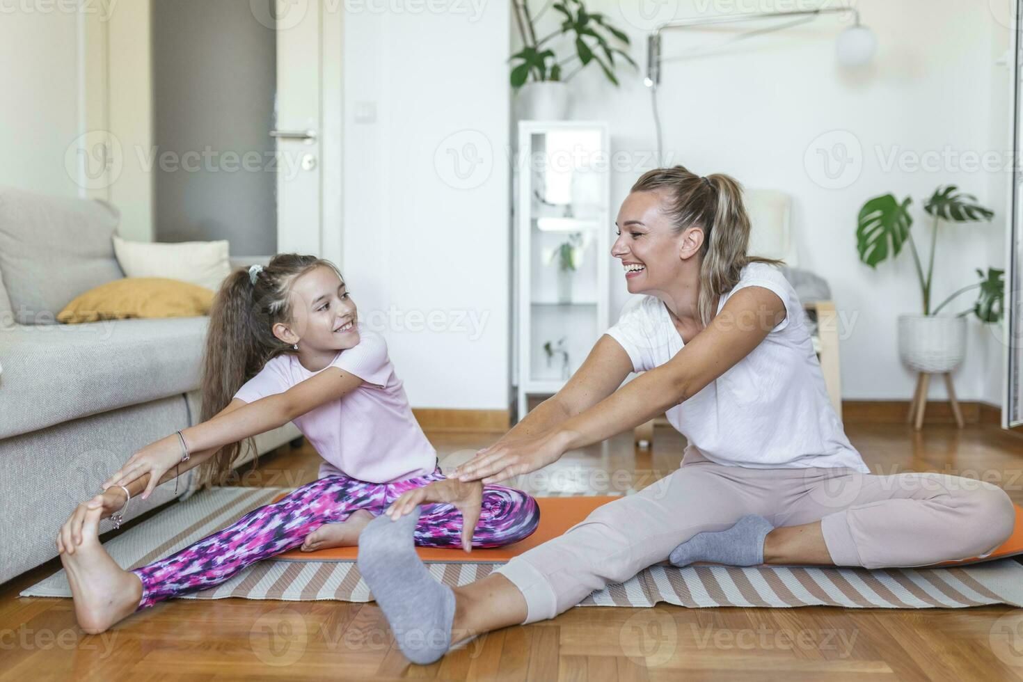 alegre joven mujer y pequeño niña en ropa de deporte hacer ejercicio juntos  en moderno ligero habitación. madre y hija practicando yoga 25887870 Foto  de stock en Vecteezy