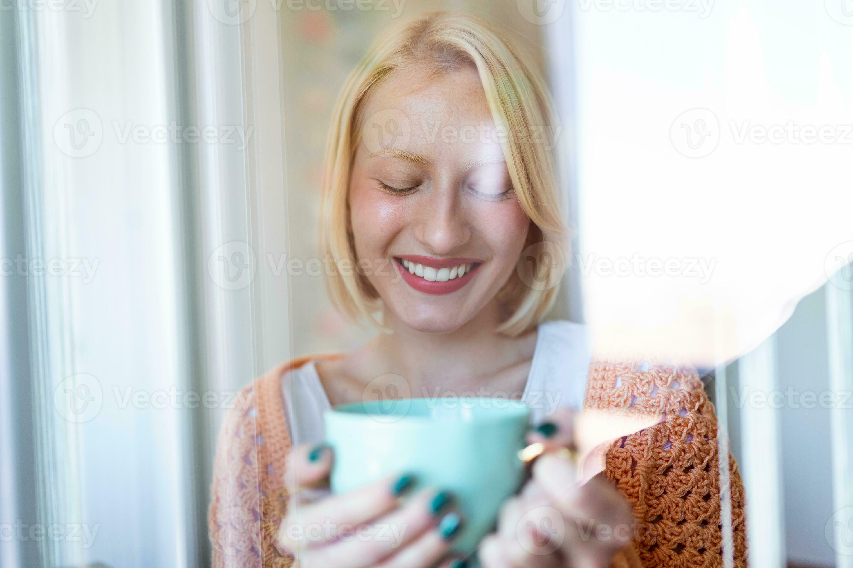 beautiful woman drinking coffee in the morning sitting by the window