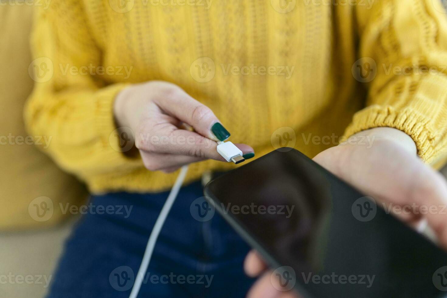 Woman hands plugging a charger in a smart phone. Woman using smartphone with powerbank, charging power to smart phone. Woman charging battery on mobile phone at home photo