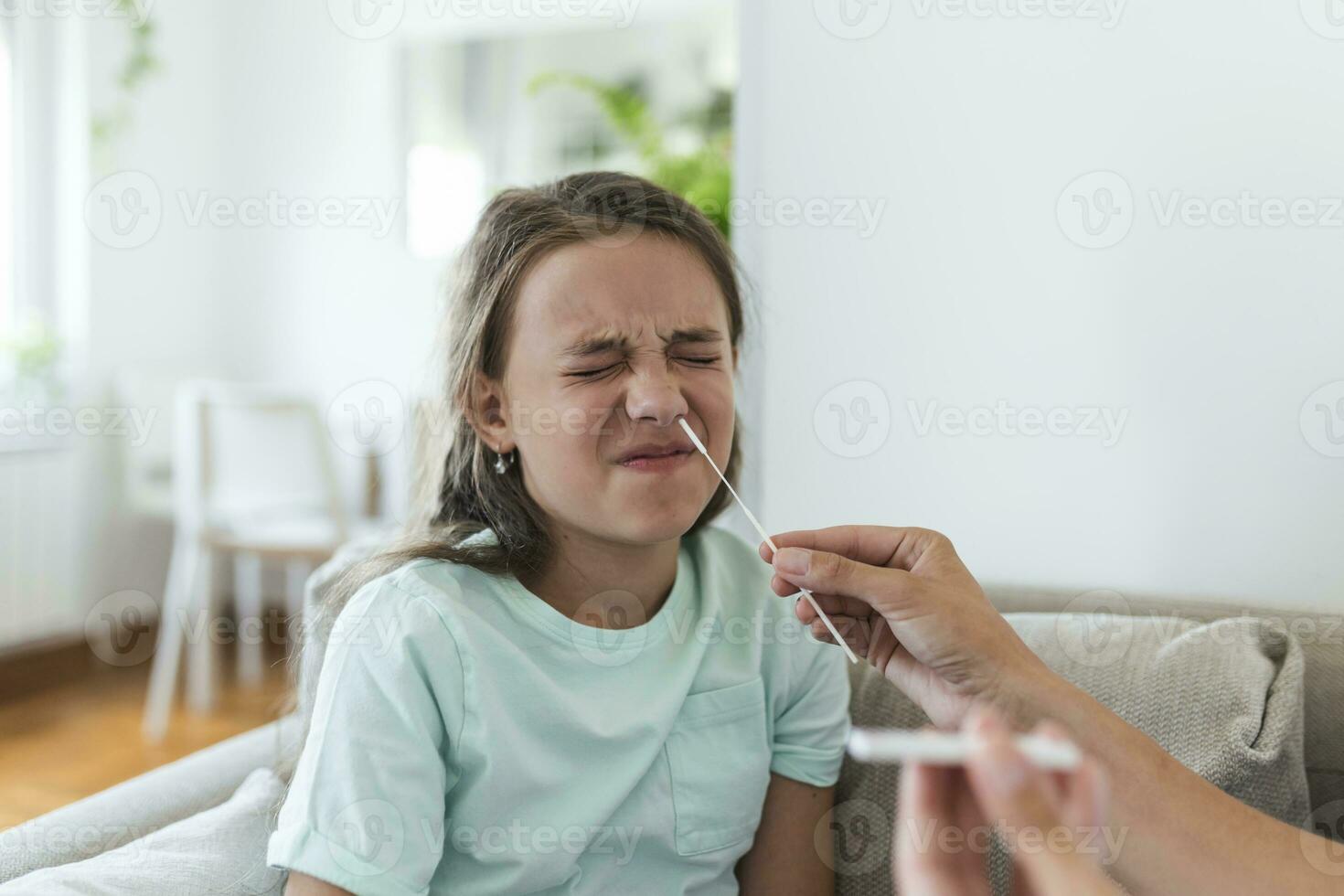 Mother is taking rapid covid-19 test at home to her sick daughter at home. Mom testing young girl for coronavirus infection taking rapid COVID-19 test photo