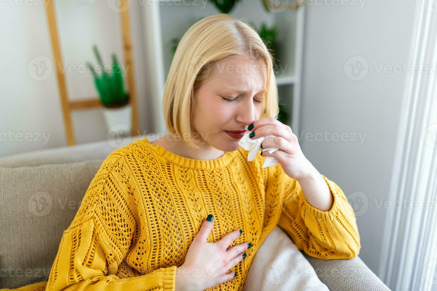 Sick Woman.Flu.Woman Caught Cold. Sneezing into Tissue. Headache. Virus .Medicines. Young Woman Infected With covid 19 Blowing Her Nose In Handkerchief. Sick woman with a headache sitting on a sofa photo