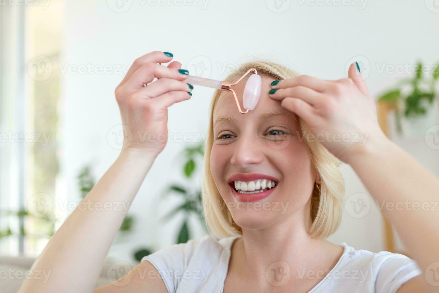 Woman doing self massage with rose quartz face roller photo