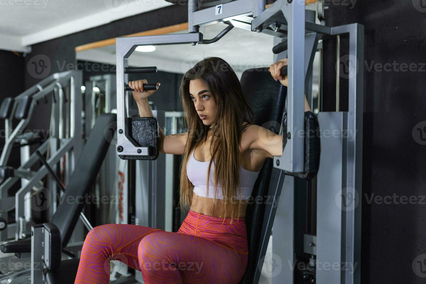 Young woman doing exercise on a chest machine fly in the gym. Women wear sportswear flexing arm muscles on chest machine fly in gym photo