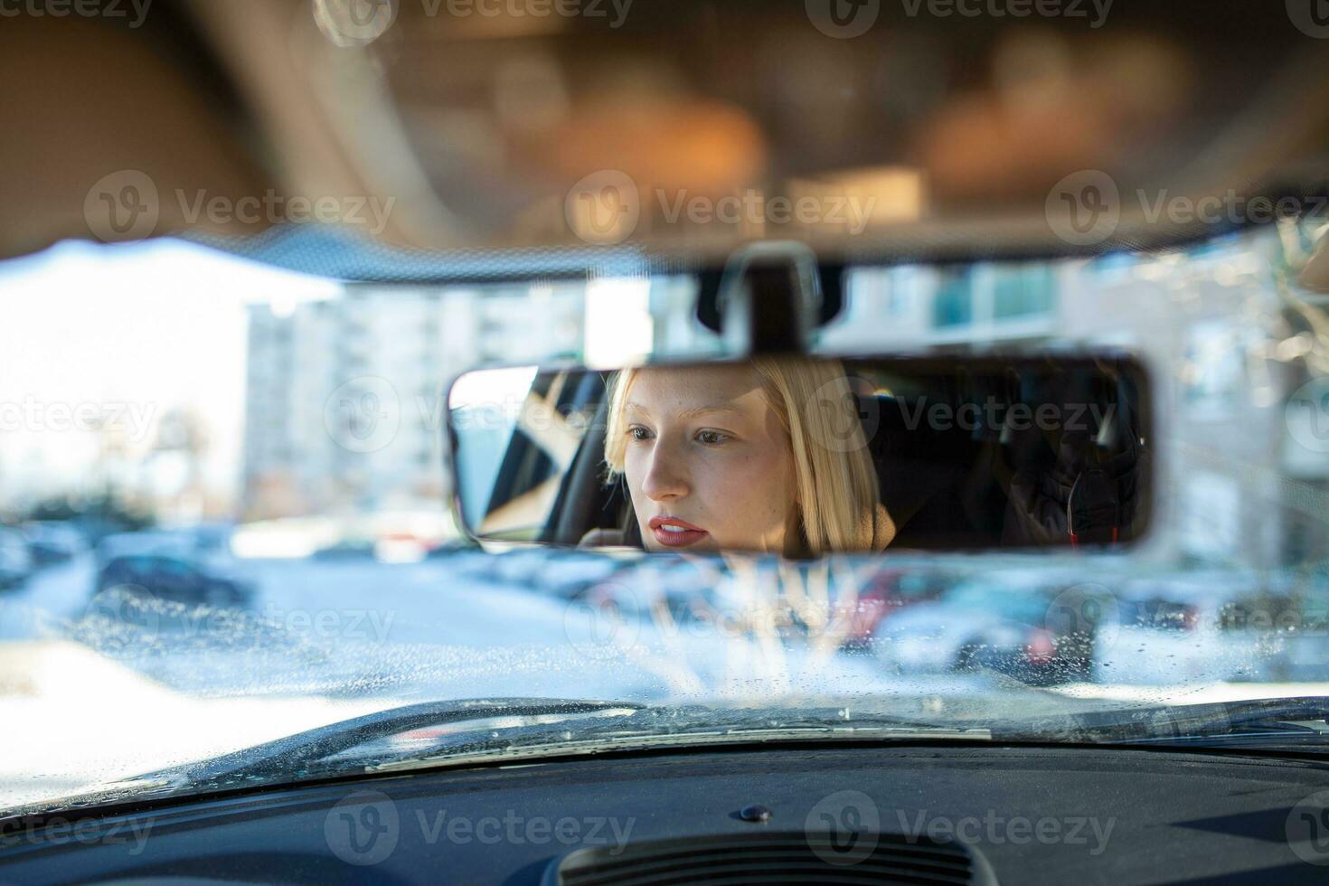 Woman hand adjusting rear view mirror of her car. Happy young woman driver looking adjusting rear view car mirror, making sure line is free visibility is good photo