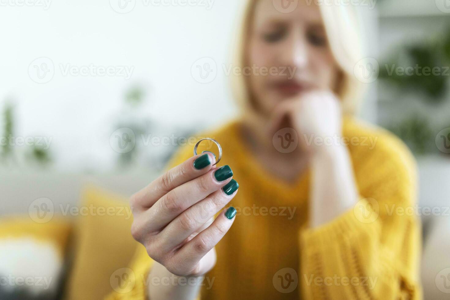 Young woman holding wedding engagement ring in hands, engaged girl doubts about marriage proposal, abandoned wife depressed after getting divorced, help to overcome breaking up, starting new life photo