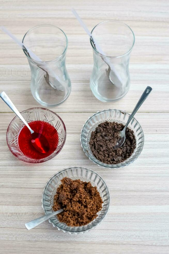 Ingredients of sundae dish as a part of non fire cooking which includes vanilla ice cream, brownie, coco powder, freshly chopped fruits and strawberry syrup. Preparation of sundae dish photo