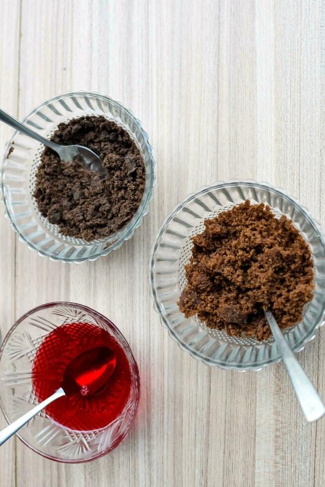 Ingredients of sundae dish as a part of non fire cooking which includes vanilla ice cream, brownie, coco powder, freshly chopped fruits and strawberry syrup. Preparation of sundae dish photo