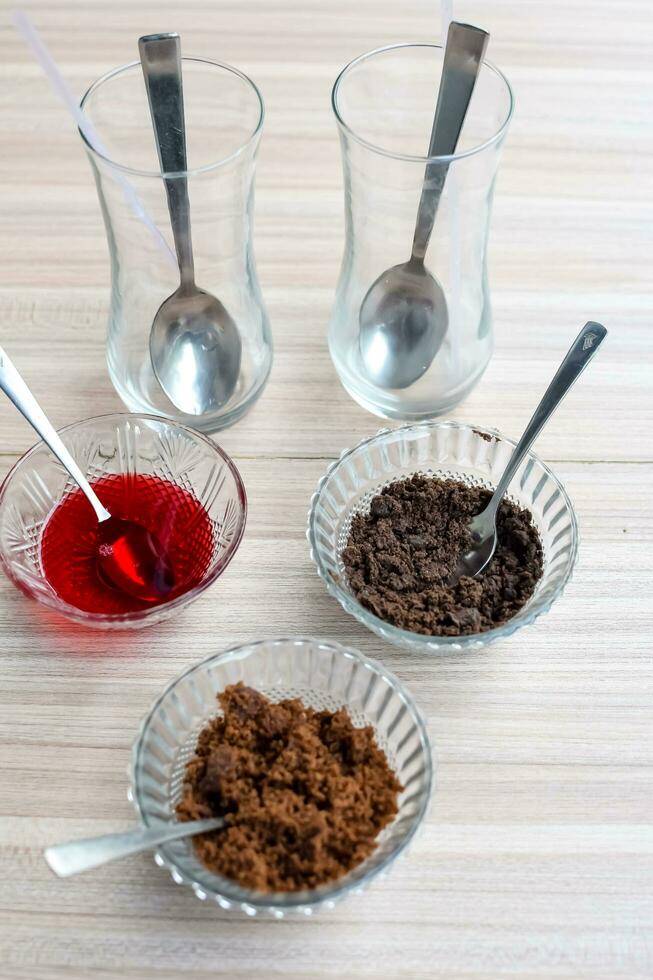 Ingredients of sundae dish as a part of non fire cooking which includes vanilla ice cream, brownie, coco powder, freshly chopped fruits and strawberry syrup. Preparation of sundae dish photo