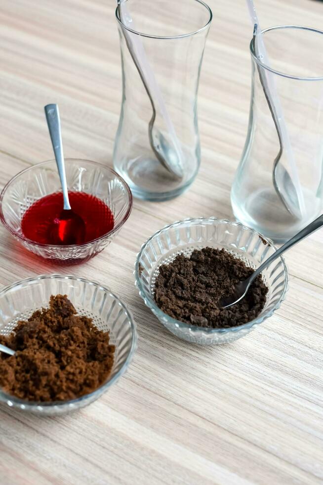 Ingredients of sundae dish as a part of non fire cooking which includes vanilla ice cream, brownie, coco powder, freshly chopped fruits and strawberry syrup. Preparation of sundae dish photo
