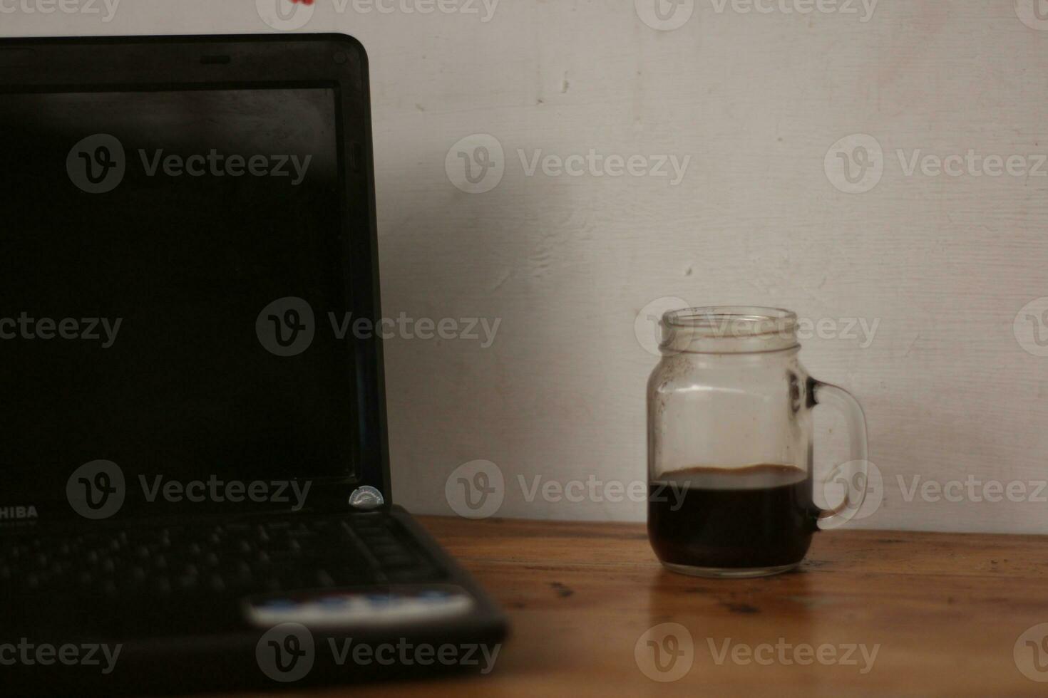 Selective focus of black coffee in glass cup on wooden table on white background. photo
