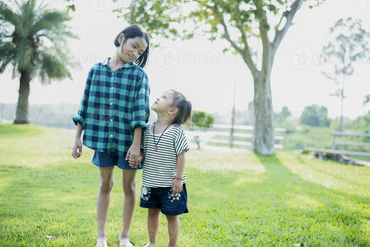 Happy Southeast Asian girls playing outdoors in the spring park. Asian children playing in the garden Summer vacation. photo