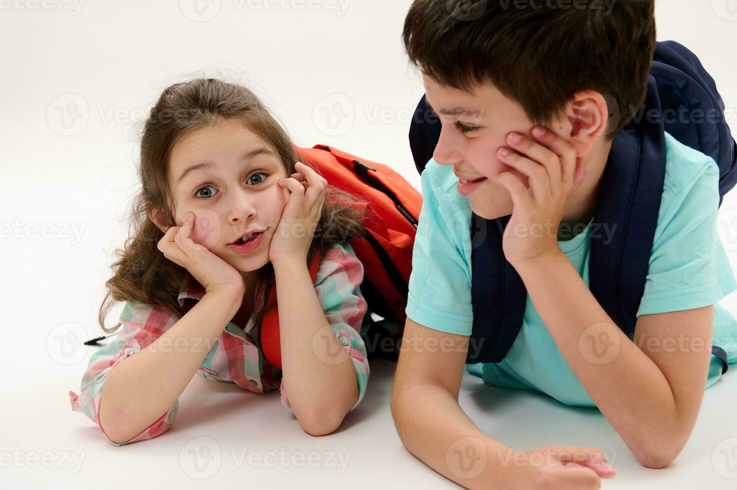 Smart school kids, first grader little child girl and preteen schoolboy, lying on belly, smiling over white background photo