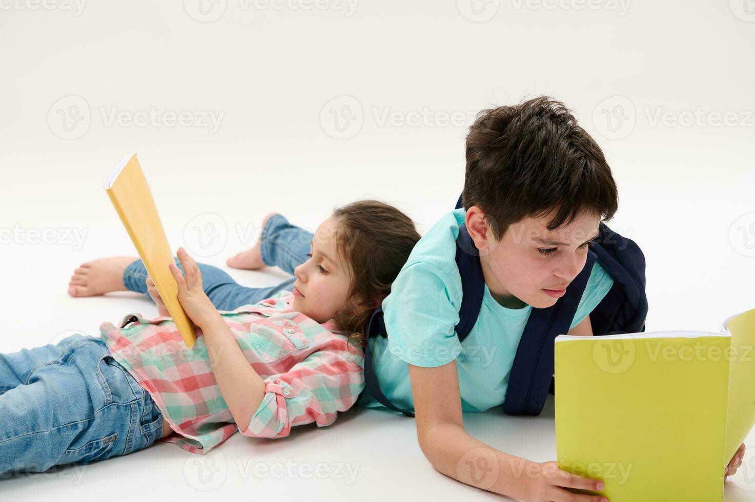 preescolar niña y Adolescente chico participación libros de trabajo, acostado en un blanco antecedentes. hermano y hermana haciendo deberes foto