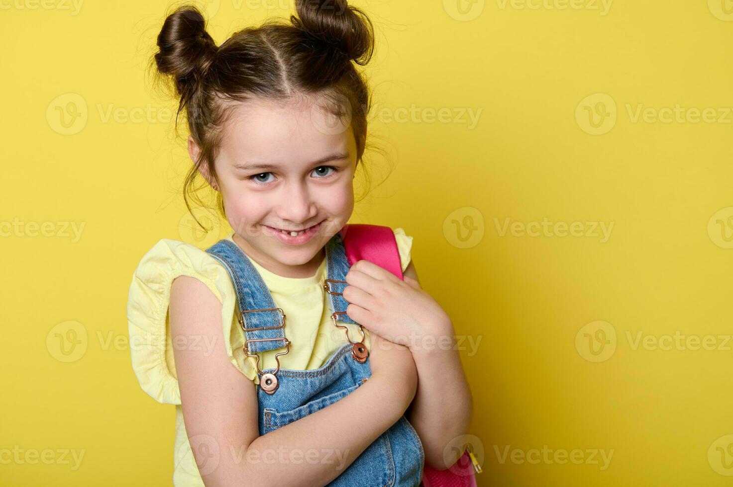 dañoso travieso pequeño niño niña con rosado mochila, sonriente mirando a cámara. Chica de escuela. primario colegio estudiante foto