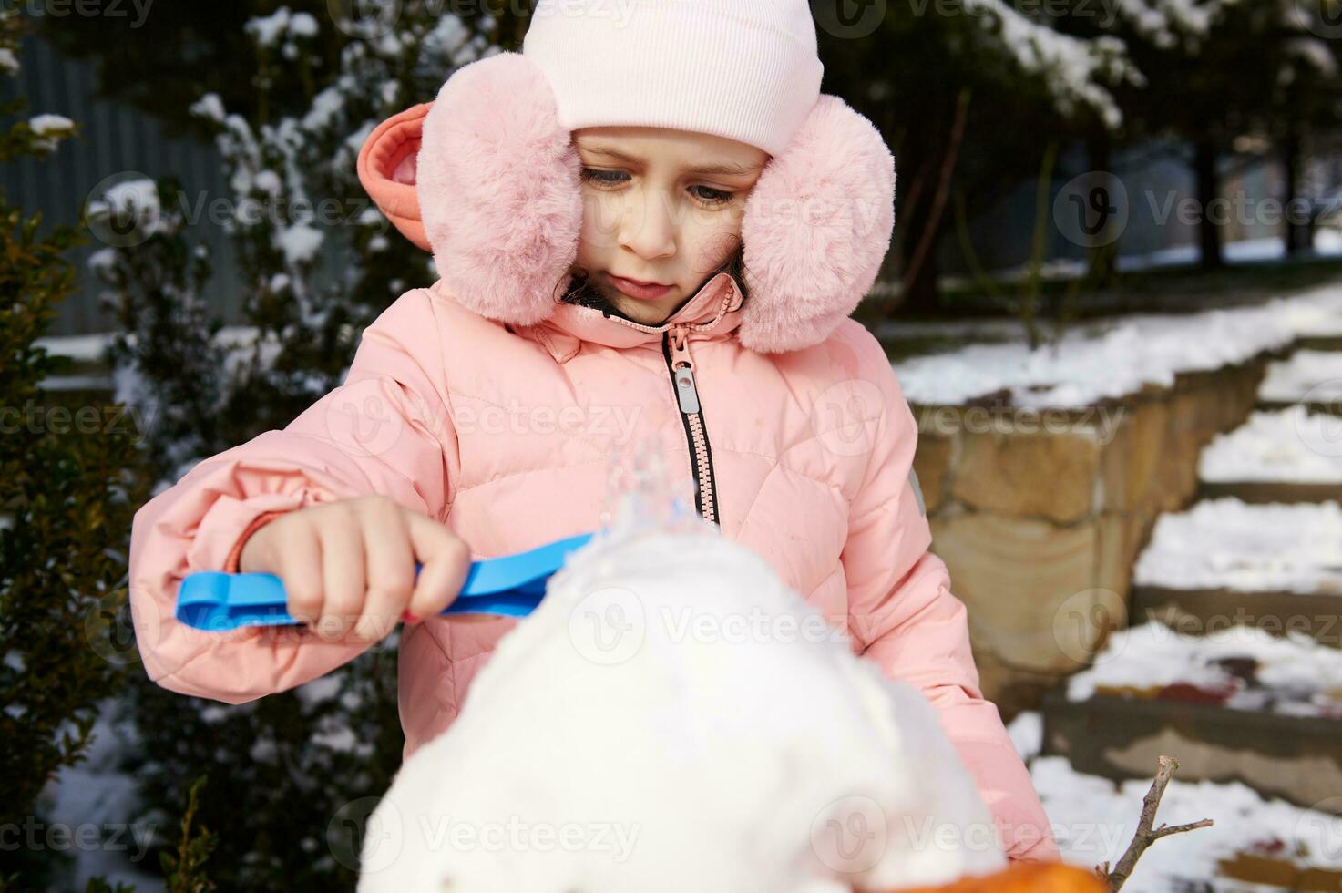 Niña del niño caucásico en ropa de invierno caliente y orejeras