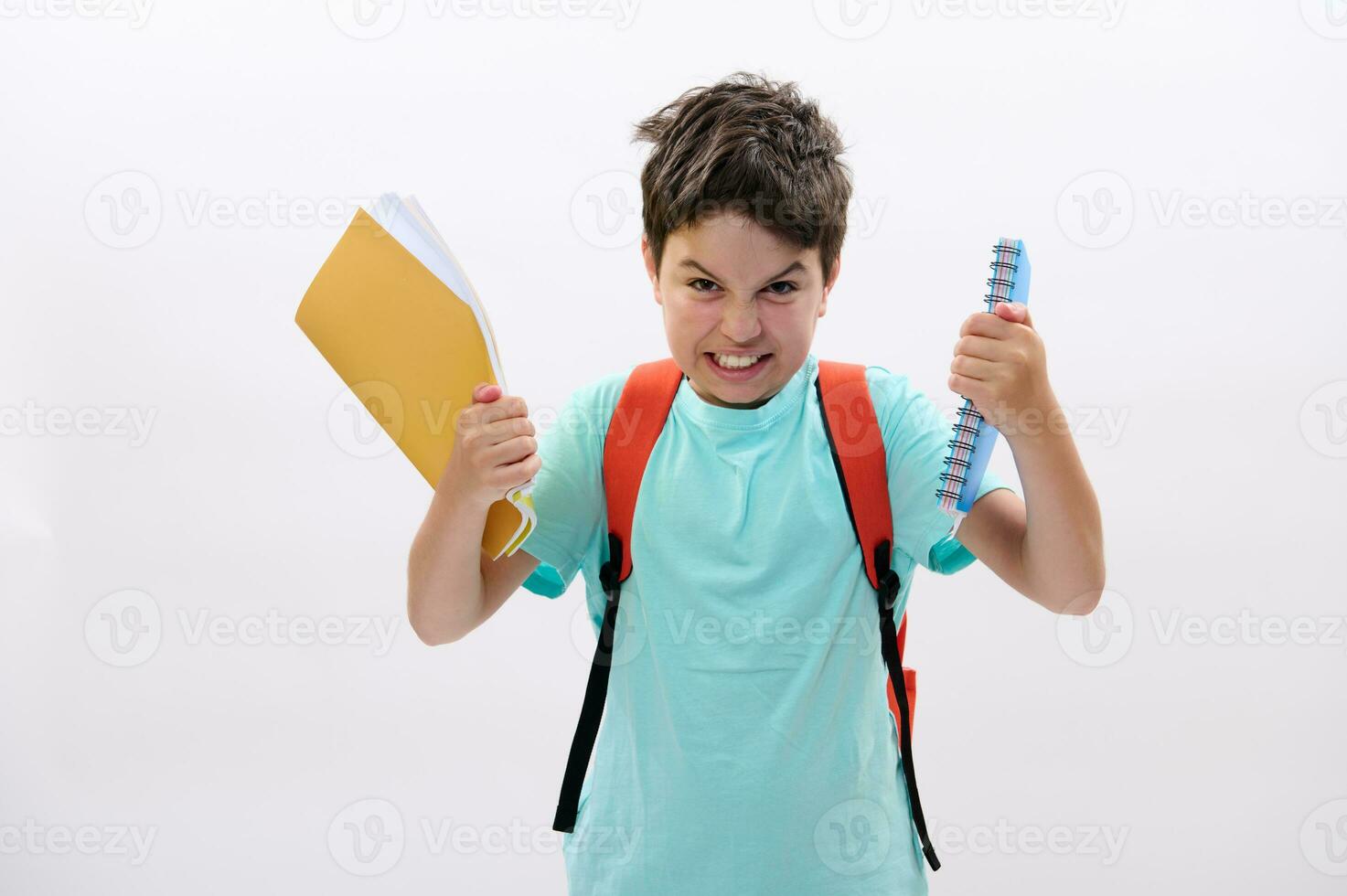 Confused angry schoolboy holding textbooks, expressing anger, irritation and frustration, isolated on white background photo