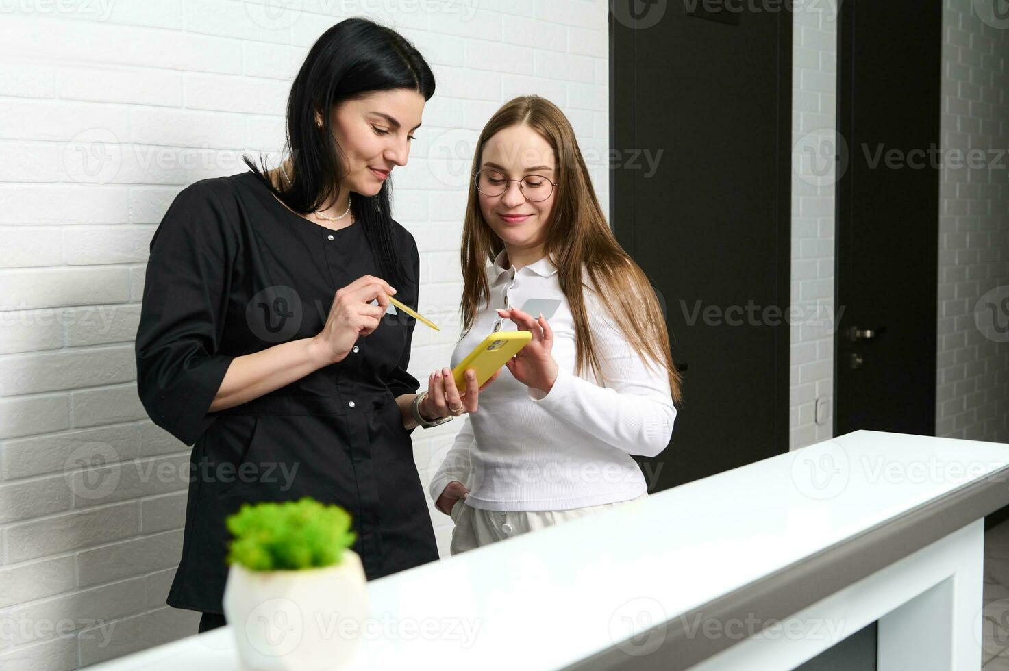 Receptionist and doctor dentist, GP or medical staff checking appointments with patients in modern medical clinic photo