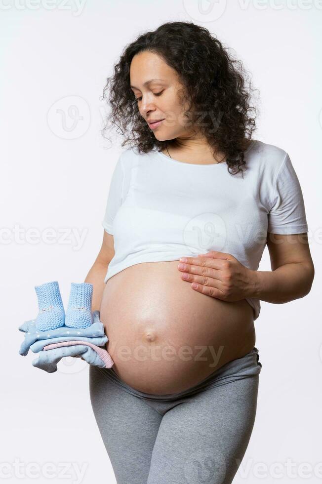 hermosa expectante mamá, embarazada mujer con bebé ropa, aislado