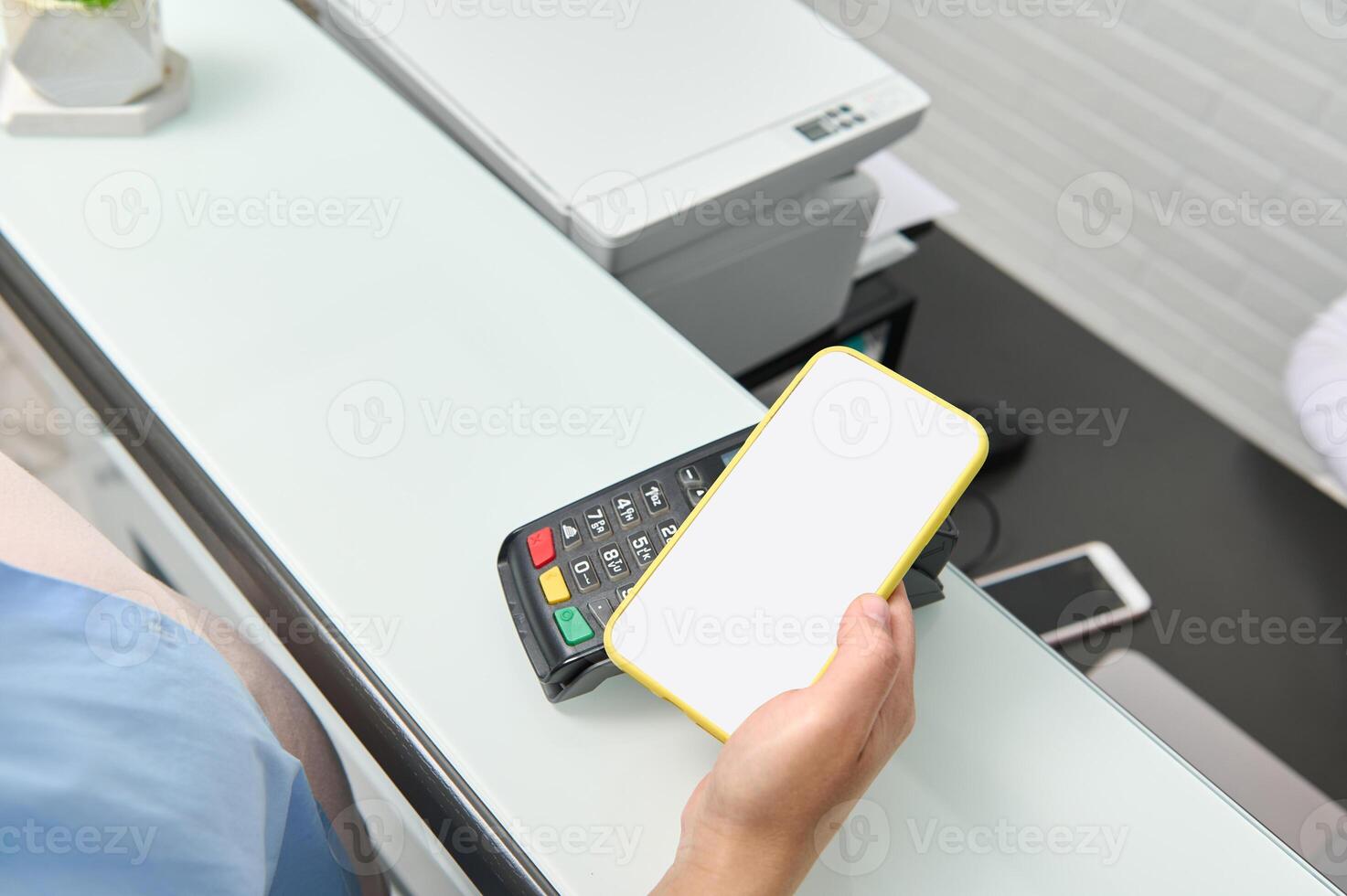 Focus on smart mobile phone with white blank mockup digital screen in customer's hand making contactless payment via NFC photo