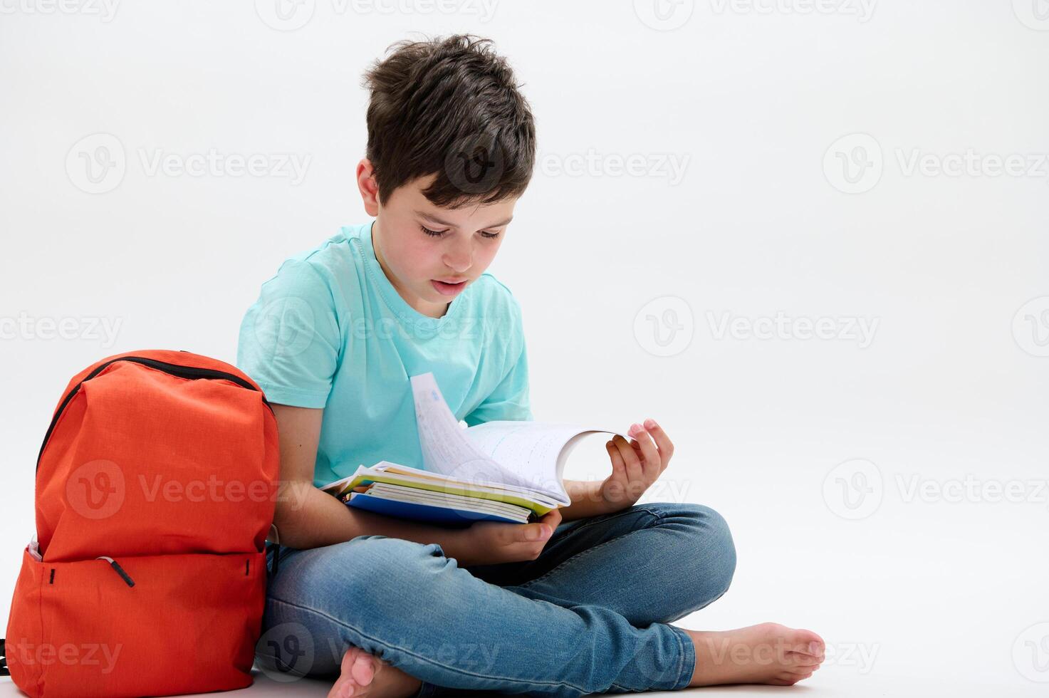 Confident smart primary school student, teenager boy 11-13 years old doing homework on his copybook, isolated on white photo
