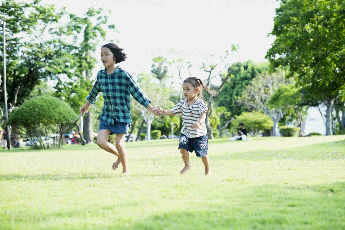 Happy Southeast Asian girls playing outdoors in the spring park. Asian children playing in the garden Summer vacation. photo