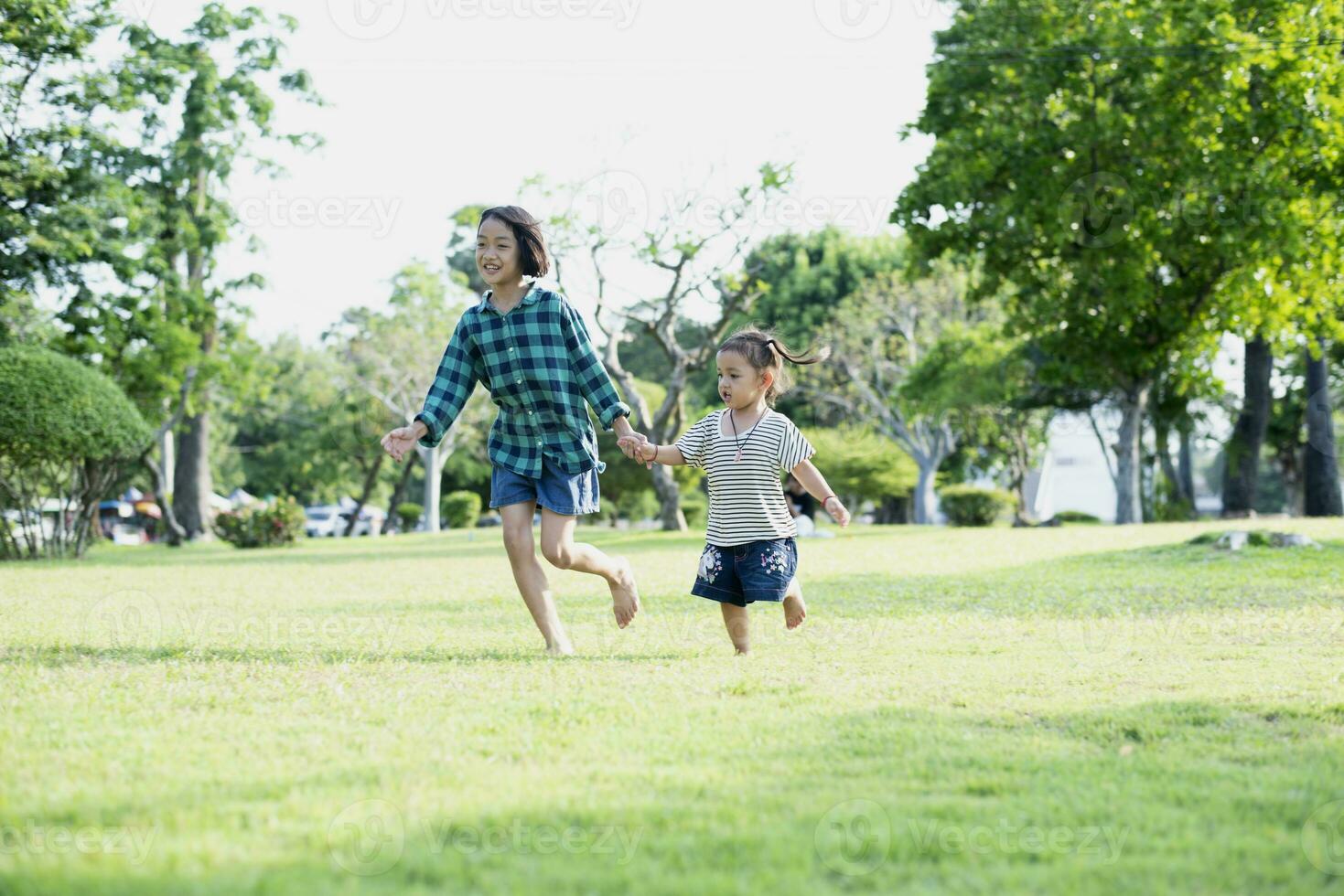 Happy Southeast Asian girls playing outdoors in the spring park. Asian children playing in the garden Summer vacation. photo