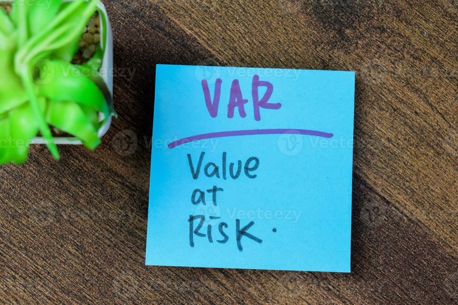 Concept of Var - Value At Risk write on sticky notes isolated on Wooden Table. photo