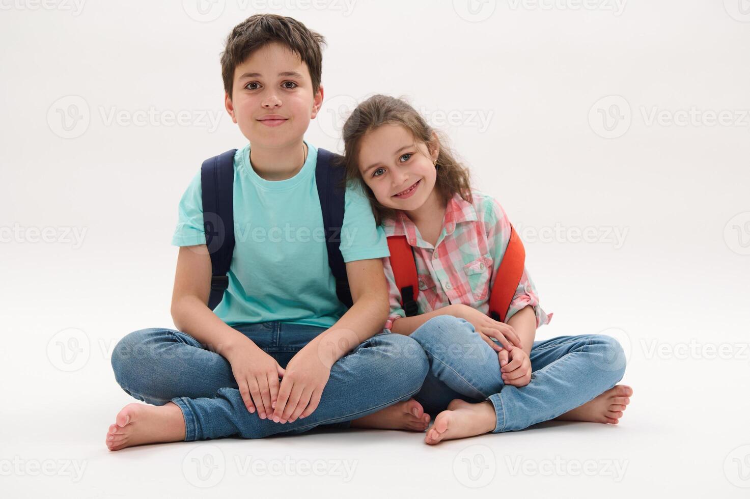 Happy school kids with backpacks, smile looking at camera, isolated over white studio background. Back to school concept photo