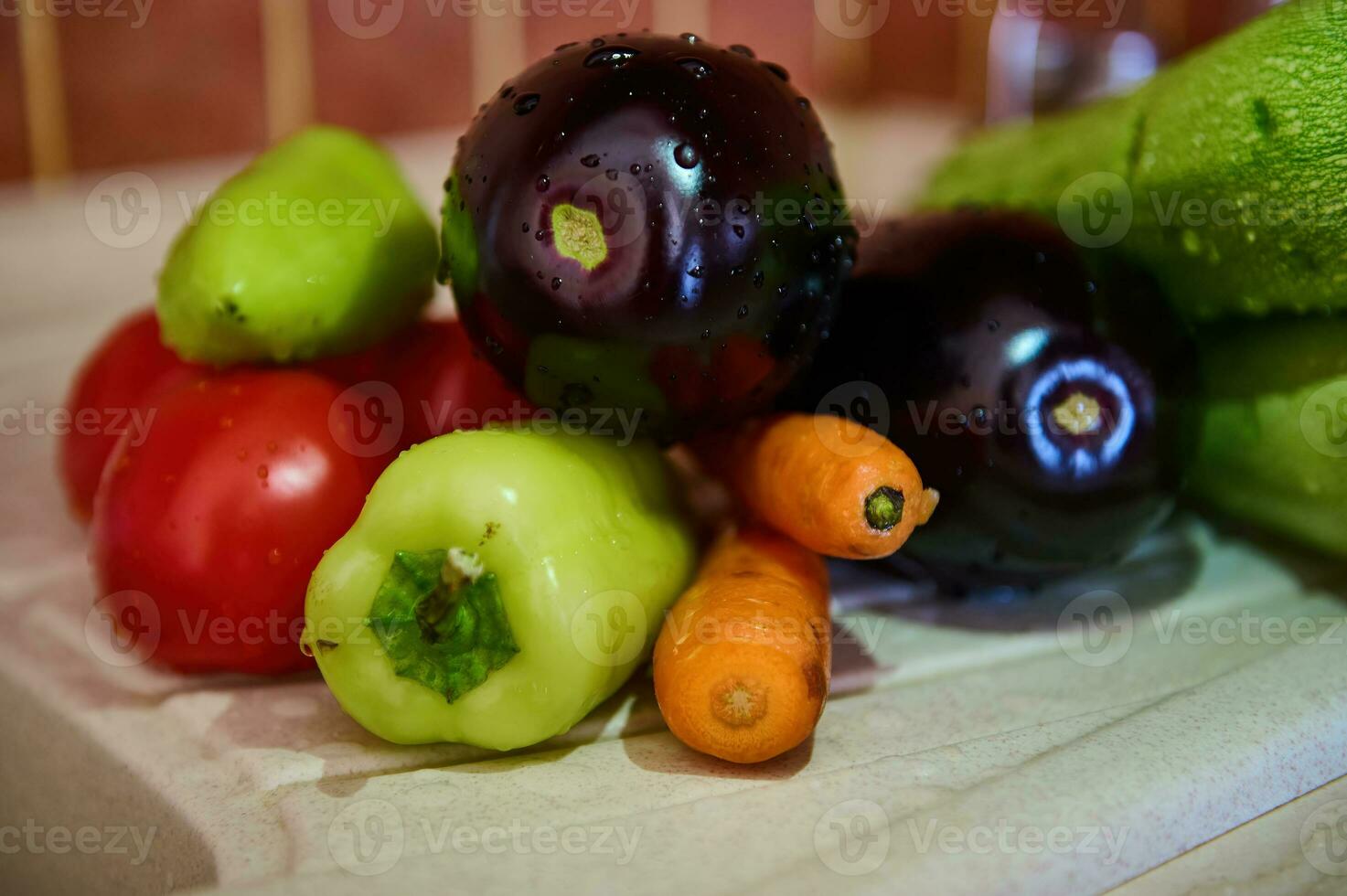 Still life with washed fresh ripe organic vegetables on a kitchen worktop. Eggplants, carrots, tomatoes, bell peppers photo