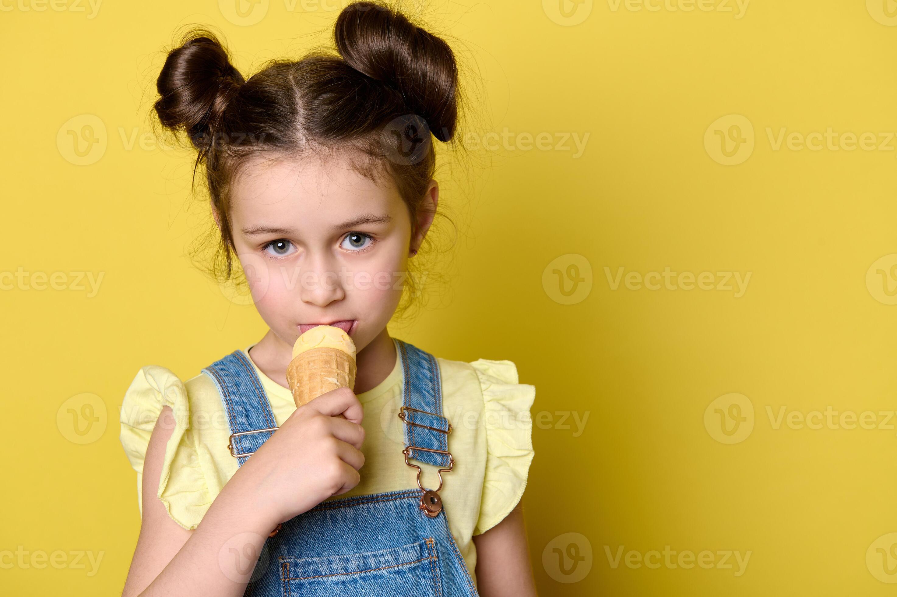 Closeup little child girl licking scoop of ice cream in waffle cone