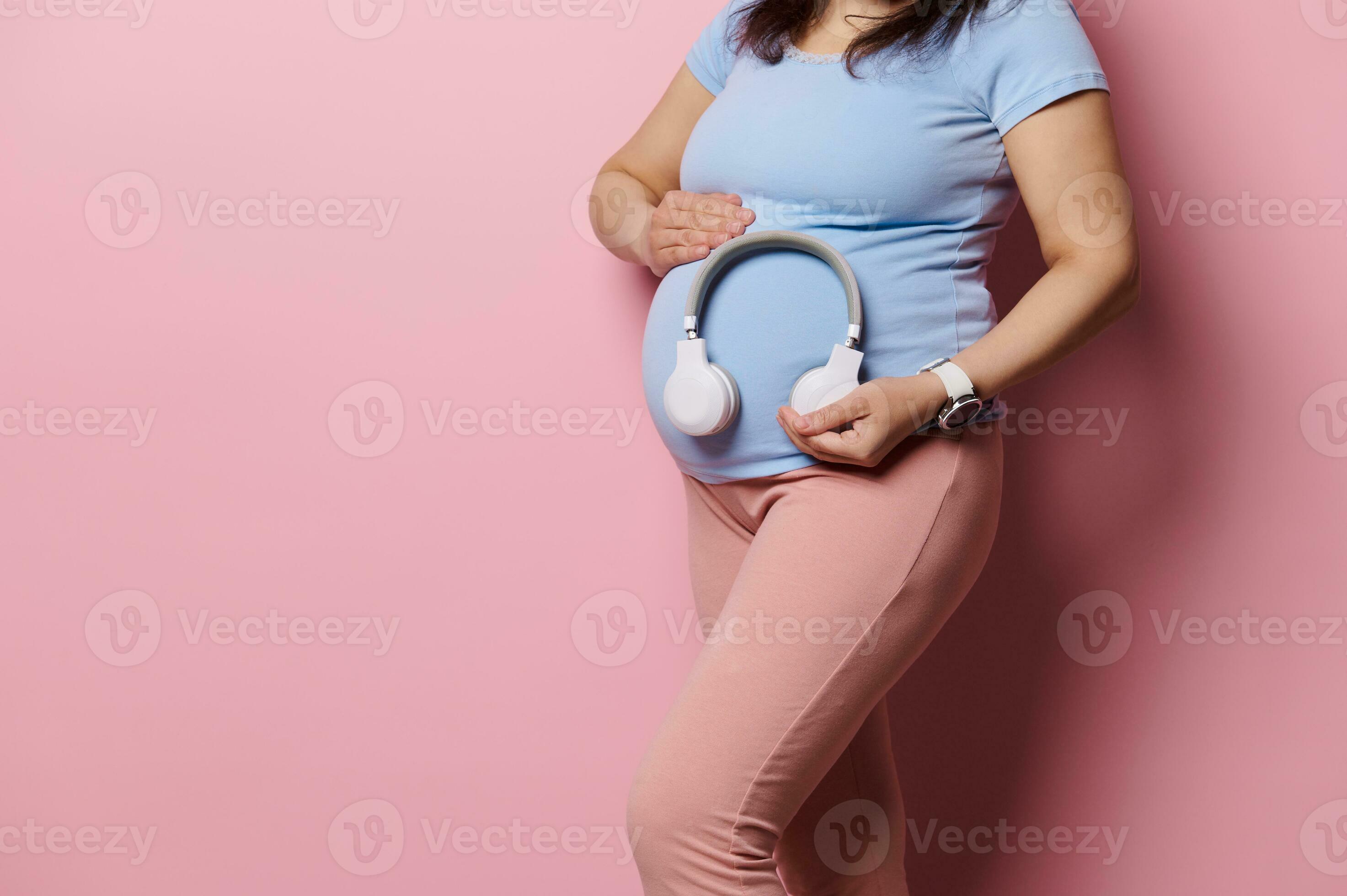 Close-up of pregnant woman putting wireless headphones over her belly,  turning on soothing music for her baby in womb 25912412 Stock Photo at  Vecteezy