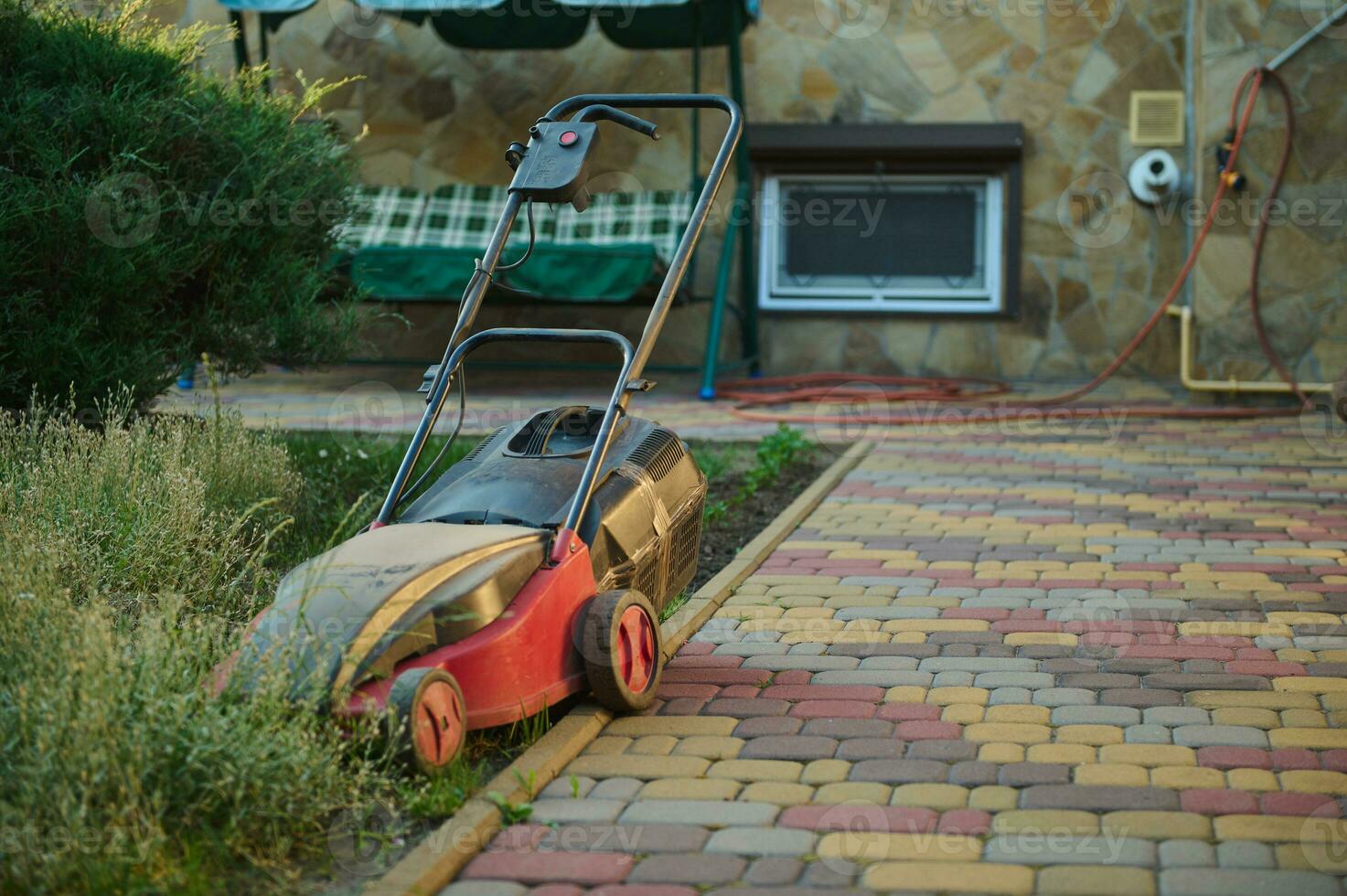 Electric lawn mower on green grass in a mansion courtyard. Landscaping indutry. Gardening. Garden maintenance concept photo