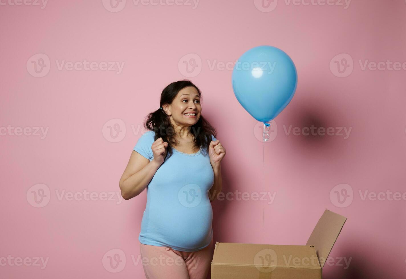 Happy pregnant woman, experiencing joy and happiness discovering blue baloon at gender reveal party. Expecting baby boy photo