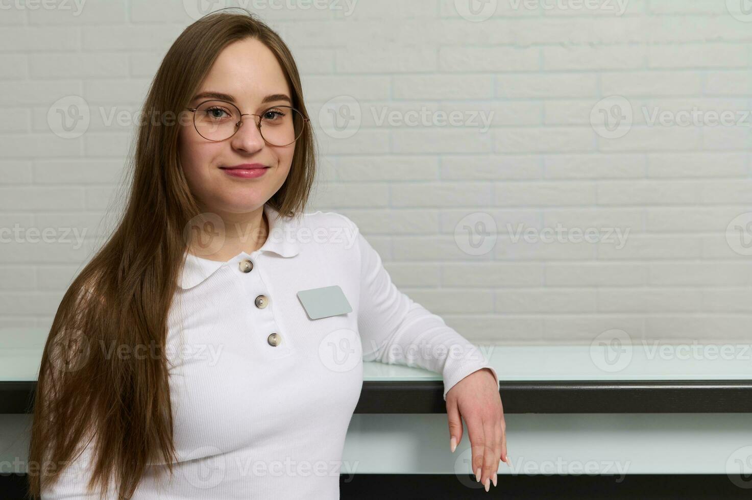 sonriente joven recepcionista en pie a el recepción escritorio en moderno médico clínica, odontología oficina o belleza spa salón foto