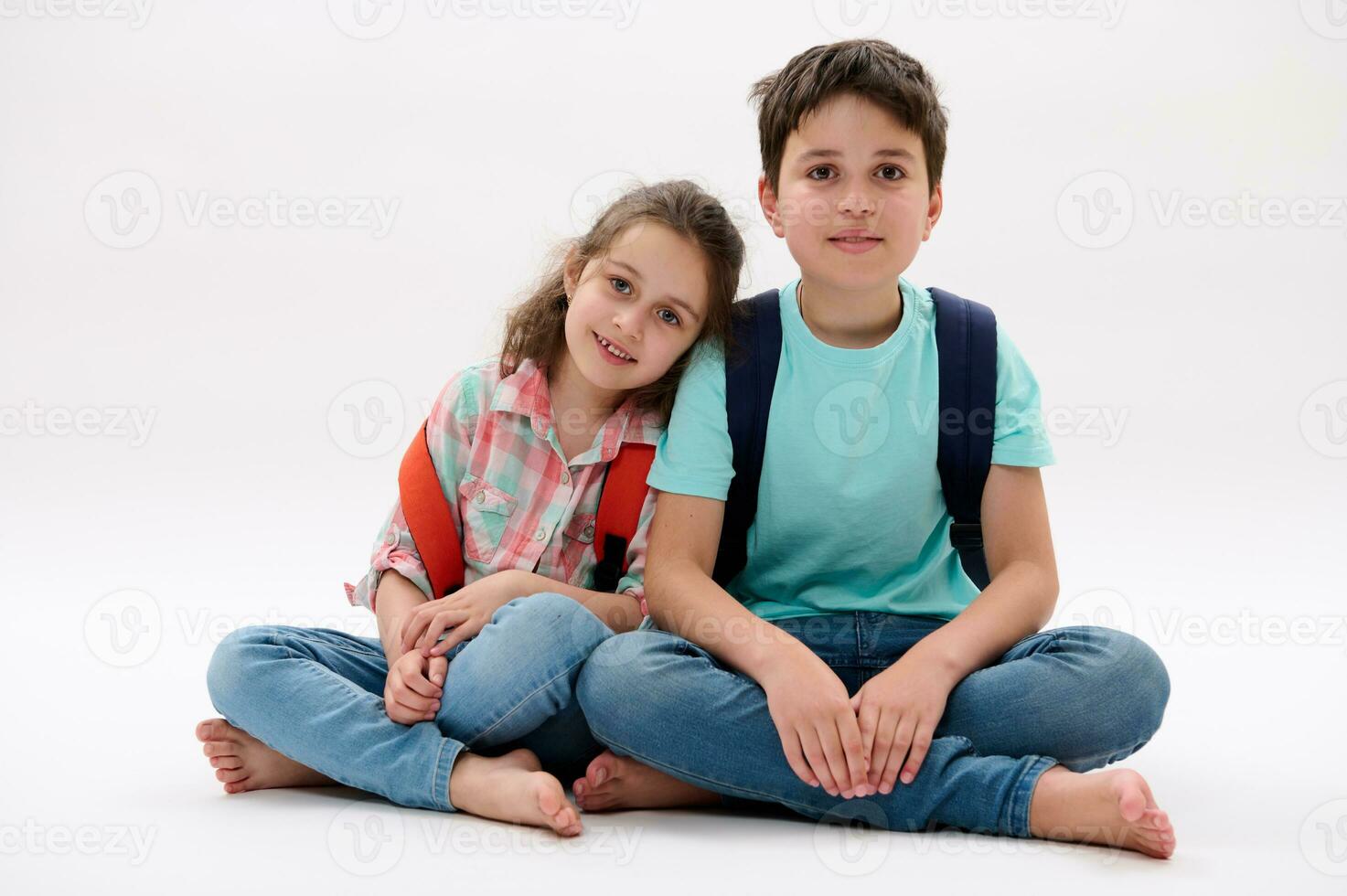 Authentic portrait of happy brother and sister, school kids with backpacks, smiling at camera, isolated white background photo