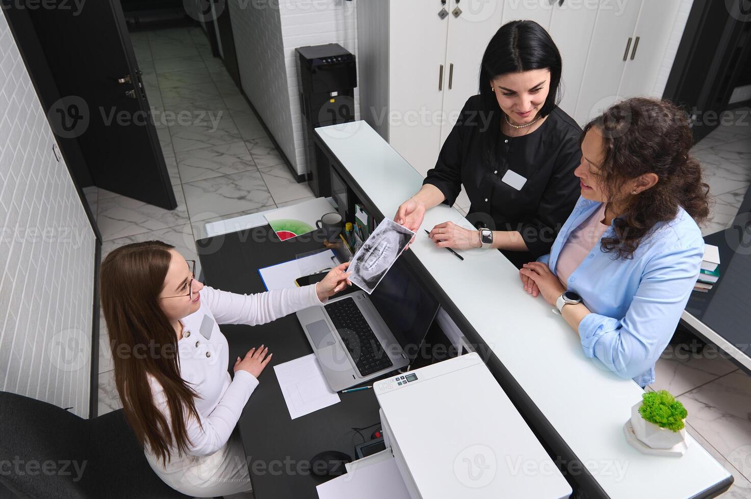 Top view happy patient and dentist standing at reception counter, prescribing treatment to perform in dentistry clinic photo