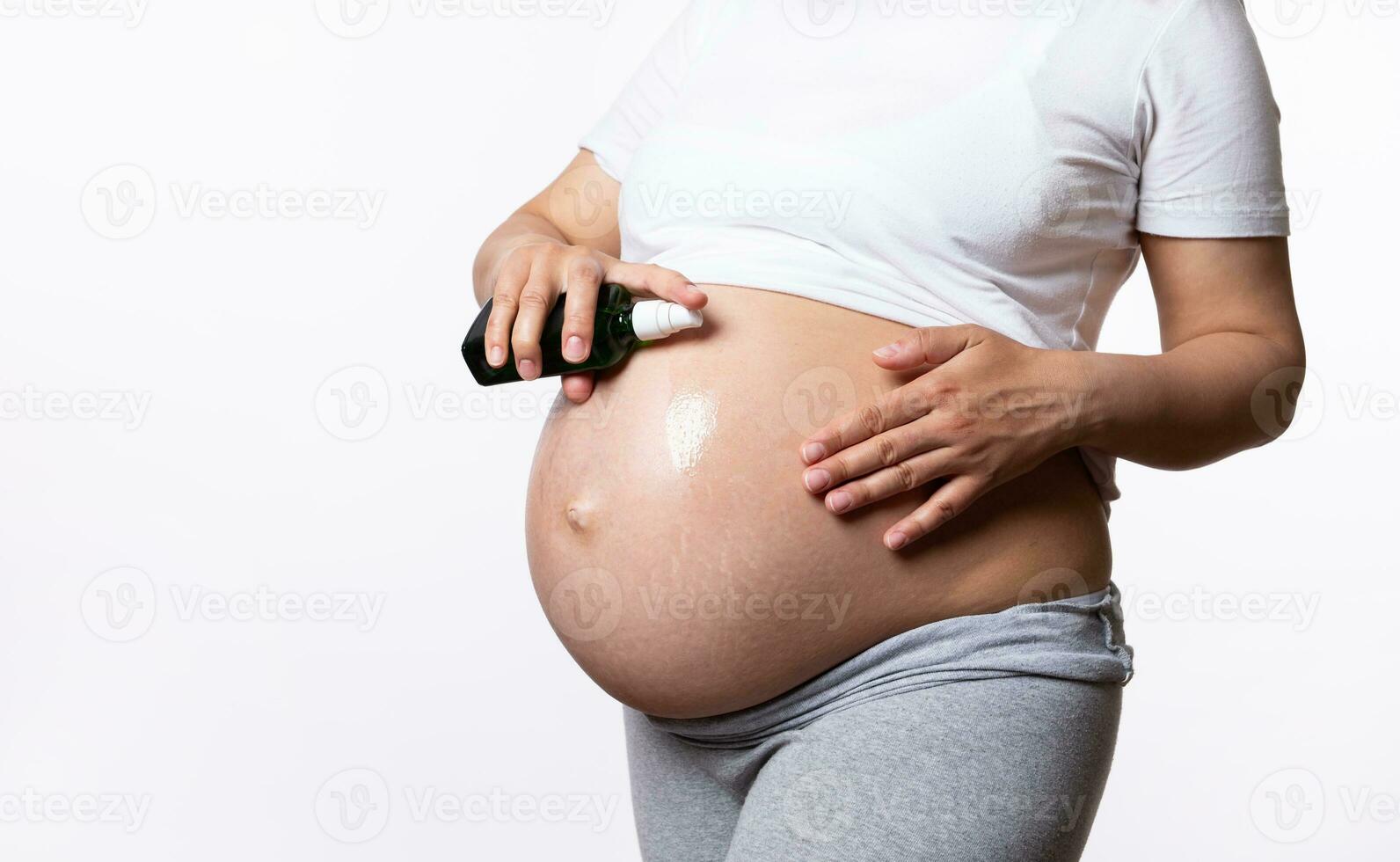 Close-up beautiful abdomen in pregnancy trimester third of a pregnant woman, applying natural smoothing cosmetic oil photo