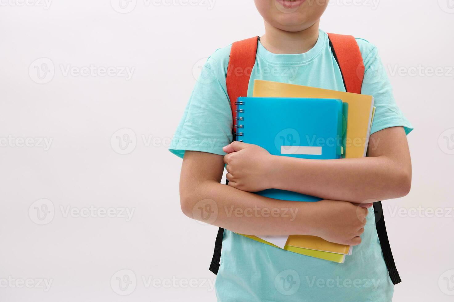 Close-up schoolboy's hands hold textbooks and workbook, isolated white studio background. Copy space. Education concept photo